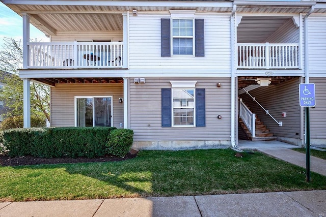 view of property with a balcony, a front yard, and stairway