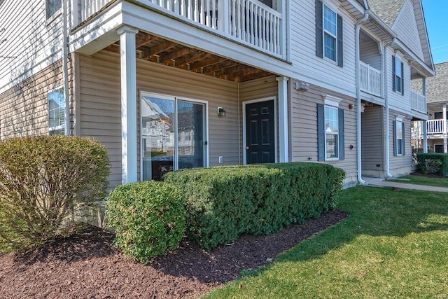 property entrance featuring a yard and a balcony