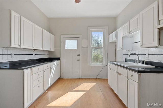 104 S 4th St, De Soto, MO 63020 - kitchen featuring dark countertops, tasteful backsplash, light wood-type flooring, and white cabinets