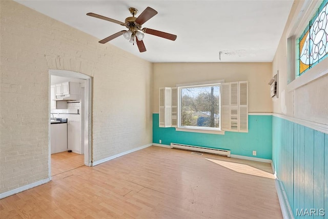 104 S 4th St, De Soto, MO 63020 - empty room with baseboard heating, wood finished floors, brick wall, ceiling fan, and a wall mounted air conditioner