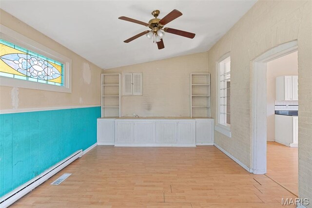 104 S 4th St, De Soto, MO 63020 - spare room featuring a baseboard radiator, a ceiling fan, wood finished floors, vaulted ceiling, and plenty of natural light