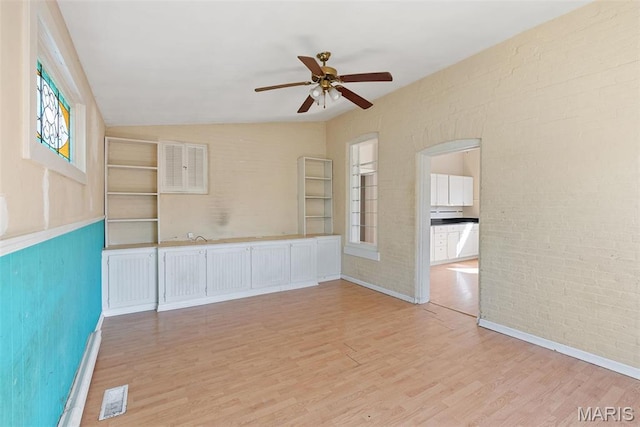 104 S 4th St, De Soto, MO 63020 - empty room featuring light wood-style flooring, ceiling fan, healthy amount of natural light, lofted ceiling, and brick wall