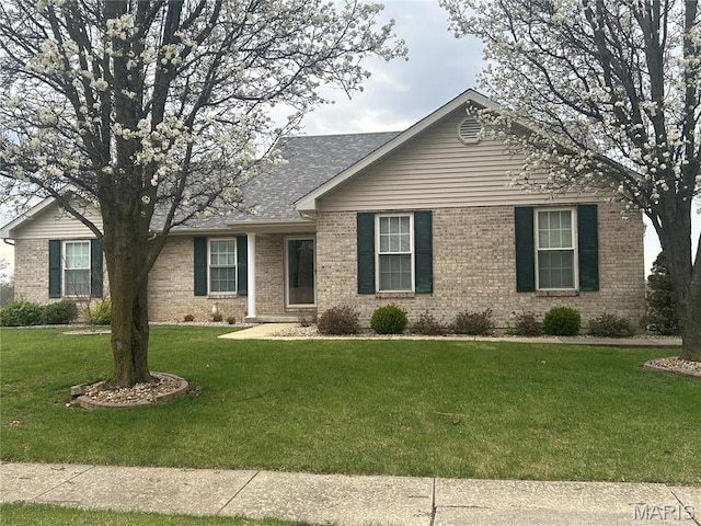 ranch-style house with brick siding, a front yard, and a shingled roof