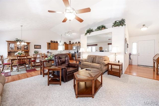 living area with lofted ceiling, ceiling fan, a chandelier, and light wood-type flooring