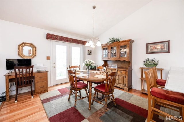 dining room featuring a chandelier, light wood finished floors, and lofted ceiling