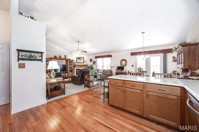 kitchen featuring a ceiling fan, light countertops, light wood finished floors, stainless steel dishwasher, and brown cabinets