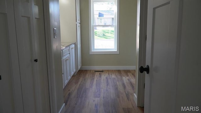 laundry area featuring baseboards, wood finished floors, and healthy amount of natural light