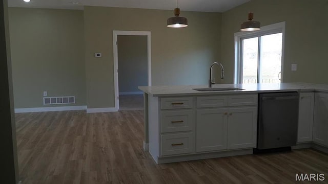 kitchen with dishwashing machine, a sink, light wood finished floors, and pendant lighting