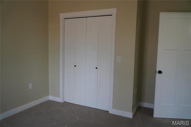 unfurnished bedroom featuring dark colored carpet, a closet, and baseboards
