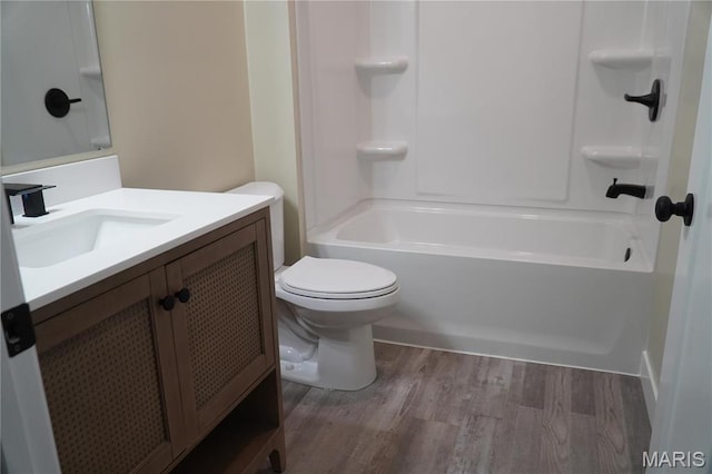 bathroom featuring wood finished floors, toilet, vanity, and bathtub / shower combination