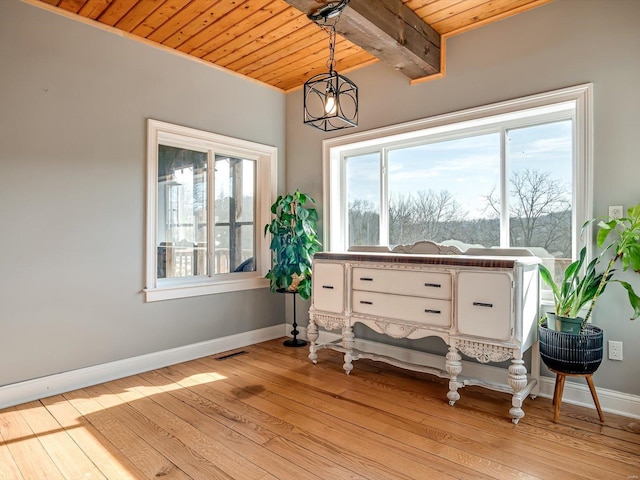 interior space with wood ceiling, healthy amount of natural light, light wood-type flooring, baseboards, and beamed ceiling