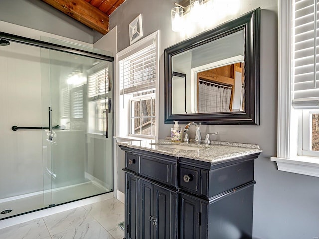 full bath featuring a stall shower, vanity, healthy amount of natural light, marble finish floors, and beam ceiling