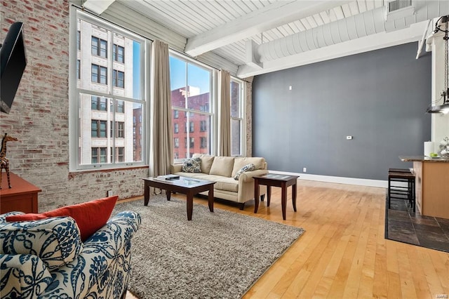 living room featuring hardwood / wood-style floors, beamed ceiling, and baseboards