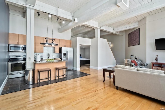 living area with light wood-type flooring, beamed ceiling, baseboards, a towering ceiling, and rail lighting
