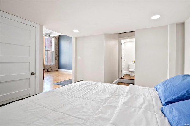 bedroom featuring baseboards, wood finished floors, recessed lighting, and ensuite bathroom