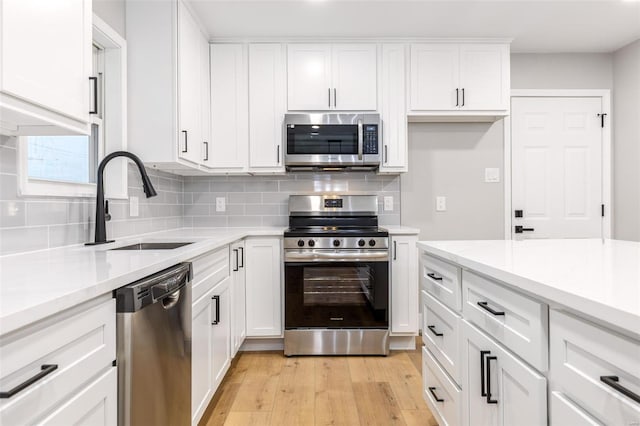 1121 E Cap Au Gris St, Troy, MO 63379 - kitchen with stainless steel appliances, a sink, light wood finished floors, and tasteful backsplash