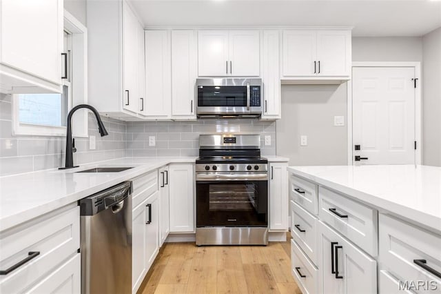 1121 E Cap Au Gris St, Troy, MO 63379 - kitchen with stainless steel appliances, a sink, light wood-style floors, and tasteful backsplash