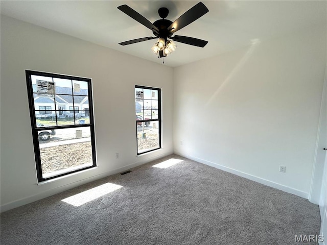 carpeted empty room featuring baseboards and a ceiling fan