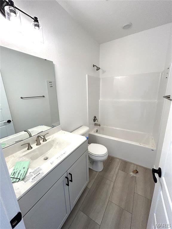 full bath featuring toilet, wood finish floors, vanity, and shower / bath combination