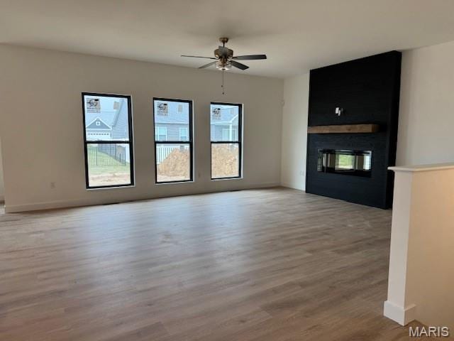 unfurnished living room featuring a ceiling fan, light wood-style flooring, a fireplace, and baseboards