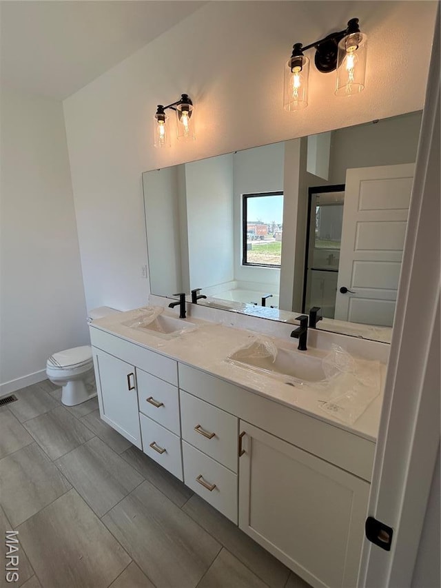 bathroom with double vanity, toilet, baseboards, and a tub