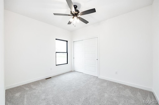 unfurnished bedroom with carpet floors, baseboards, a closet, and a ceiling fan