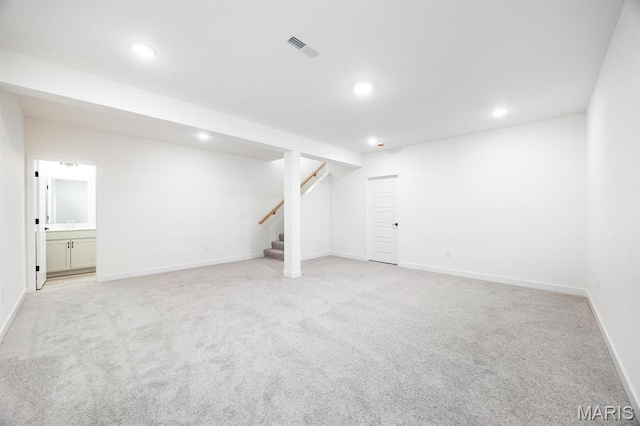 finished basement with light colored carpet, stairway, recessed lighting, and baseboards