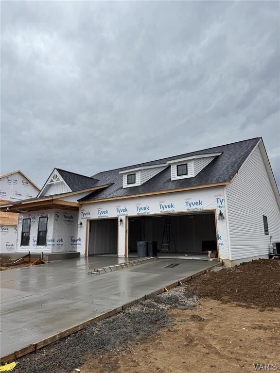 view of front facade with a garage, driveway, roof with shingles, and central air condition unit