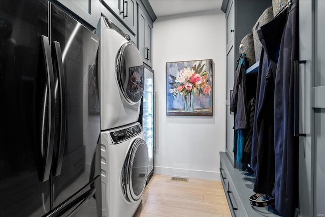 914 Memsie Park Ct, Ofallon, MO 63368 - washroom featuring stacked washer and clothes dryer, light wood-style flooring, and baseboards