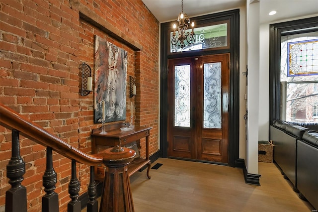 910 Lami St, Saint Louis, MO 63104 - entryway featuring light wood-style floors, a chandelier, brick wall, and baseboards