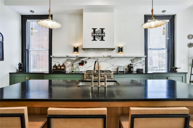 910 Lami St, Saint Louis, MO 63104 - kitchen featuring green cabinetry, dark countertops, a sink, backsplash, and decorative light fixtures