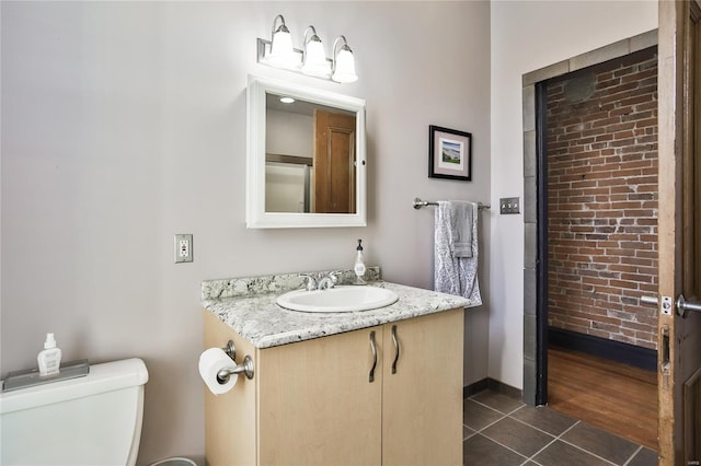 910 Lami St, Saint Louis, MO 63104 - bathroom featuring tile patterned flooring, toilet, vanity, and brick wall