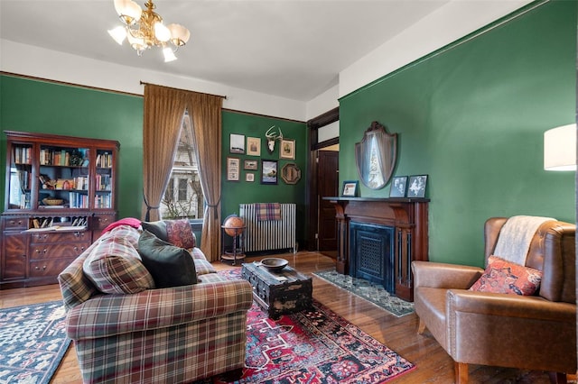 312 Bellevue St, Cape Girardeau, MO 63701 - living area featuring wood finished floors, a chandelier, radiator, and a fireplace with flush hearth
