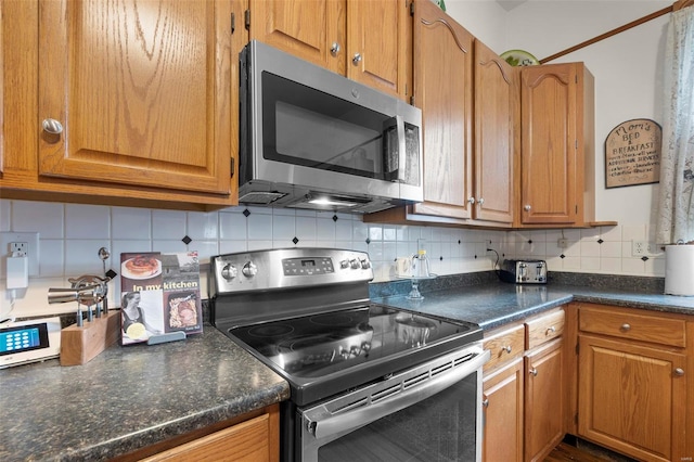 312 Bellevue St, Cape Girardeau, MO 63701 - kitchen with appliances with stainless steel finishes, tasteful backsplash, dark countertops, and brown cabinets
