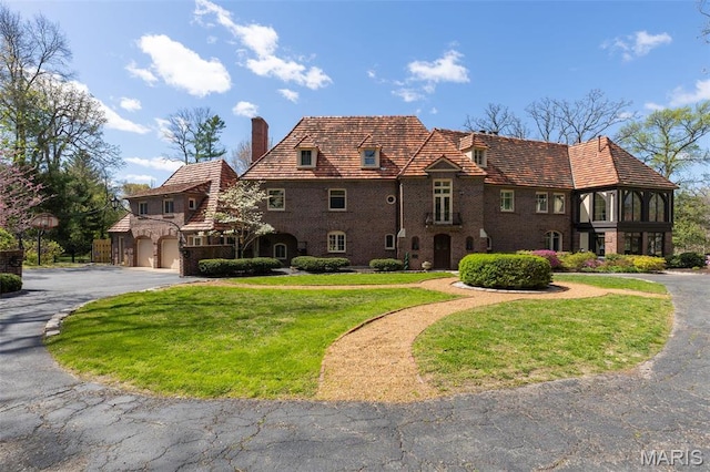 8 Carrswold Dr, Clayton, MO 63105 - tudor home with a chimney, asphalt driveway, a garage, and a front yard
