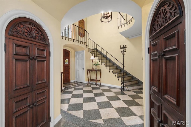 8 Carrswold Dr, Clayton, MO 63105 - entrance foyer with baseboards, arched walkways, a chandelier, stairs, and dark floors