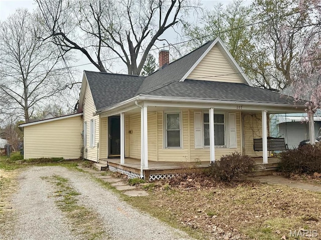 view of front of home with a porch, a shingled roof, and a chimney