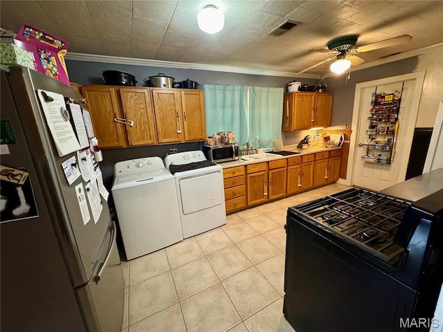 kitchen with appliances with stainless steel finishes, independent washer and dryer, brown cabinetry, crown molding, and a sink
