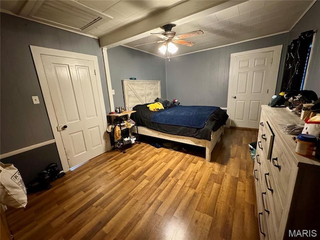 bedroom featuring wood finished floors, crown molding, wooden walls, and a ceiling fan