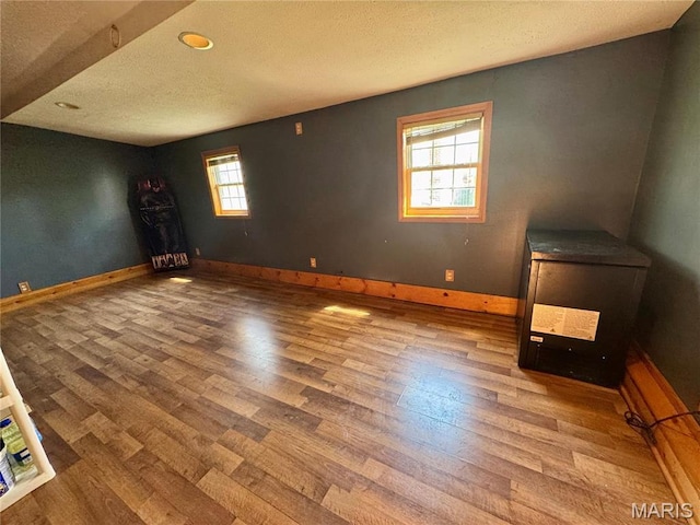 unfurnished room with wood finished floors, baseboards, and a textured ceiling