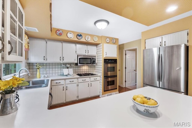 14590 Ansonborough Ct, Chesterfield, MO 63017 - kitchen with appliances with stainless steel finishes, a sink, tasteful backsplash, light countertops, and white cabinets