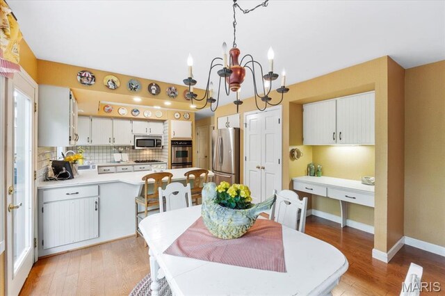 14590 Ansonborough Ct, Chesterfield, MO 63017 - kitchen with stainless steel appliances, a chandelier, backsplash, a peninsula, and light countertops