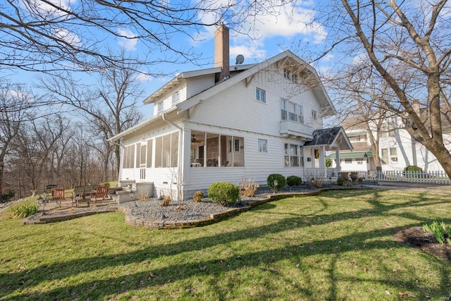 rear view of house with a sunroom, a chimney, a ceiling fan, and a patio