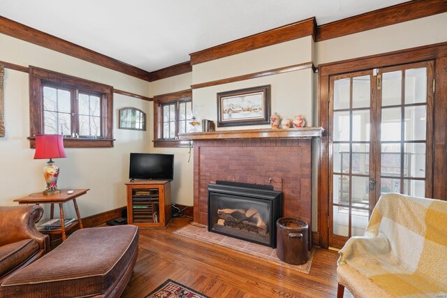 living area with wood finished floors, baseboards, and a brick fireplace