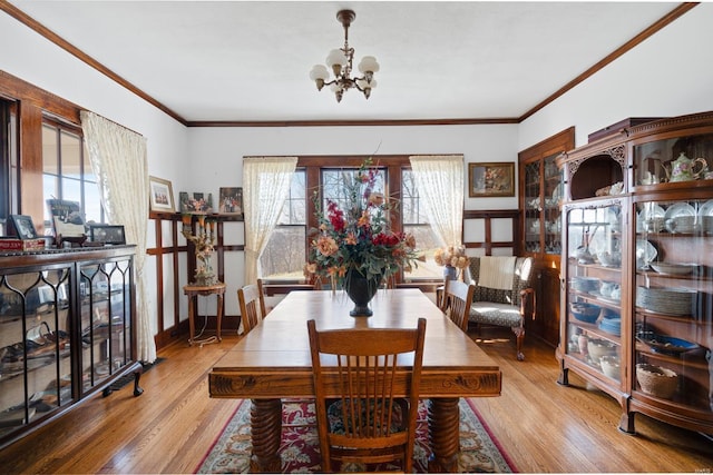 dining space with a chandelier, plenty of natural light, wood finished floors, and ornamental molding