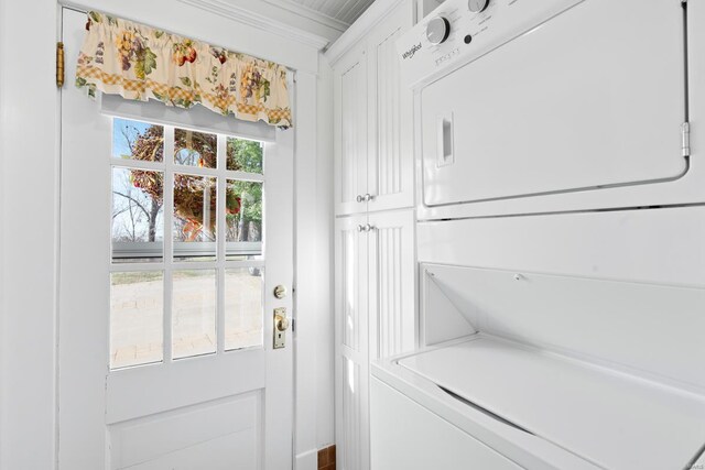 laundry room featuring stacked washer / dryer and crown molding
