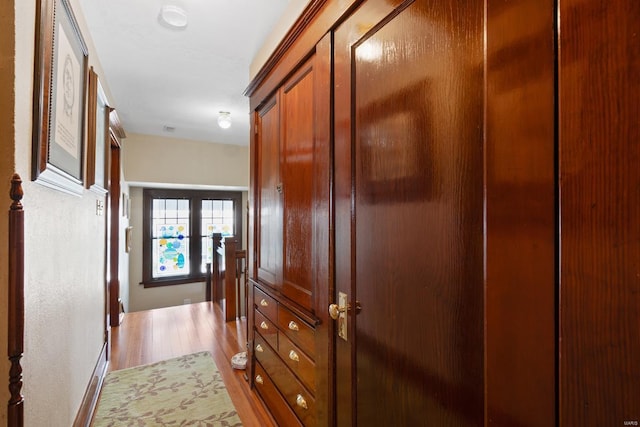 hallway featuring light wood finished floors and baseboards