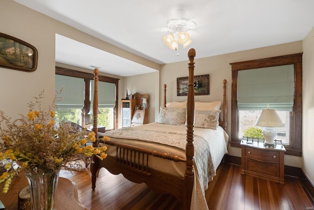 bedroom featuring multiple windows, dark wood-style flooring, and baseboards