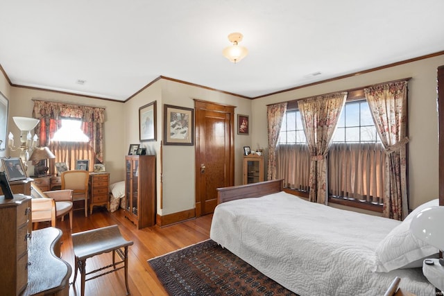 bedroom with wood finished floors, multiple windows, crown molding, and baseboards