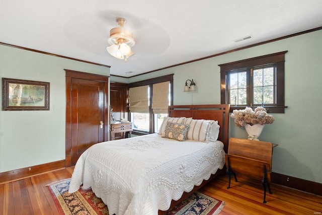 bedroom with wood-type flooring, baseboards, ornamental molding, and a ceiling fan